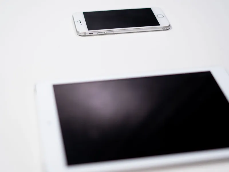 Smartphones and a tablet on a white table